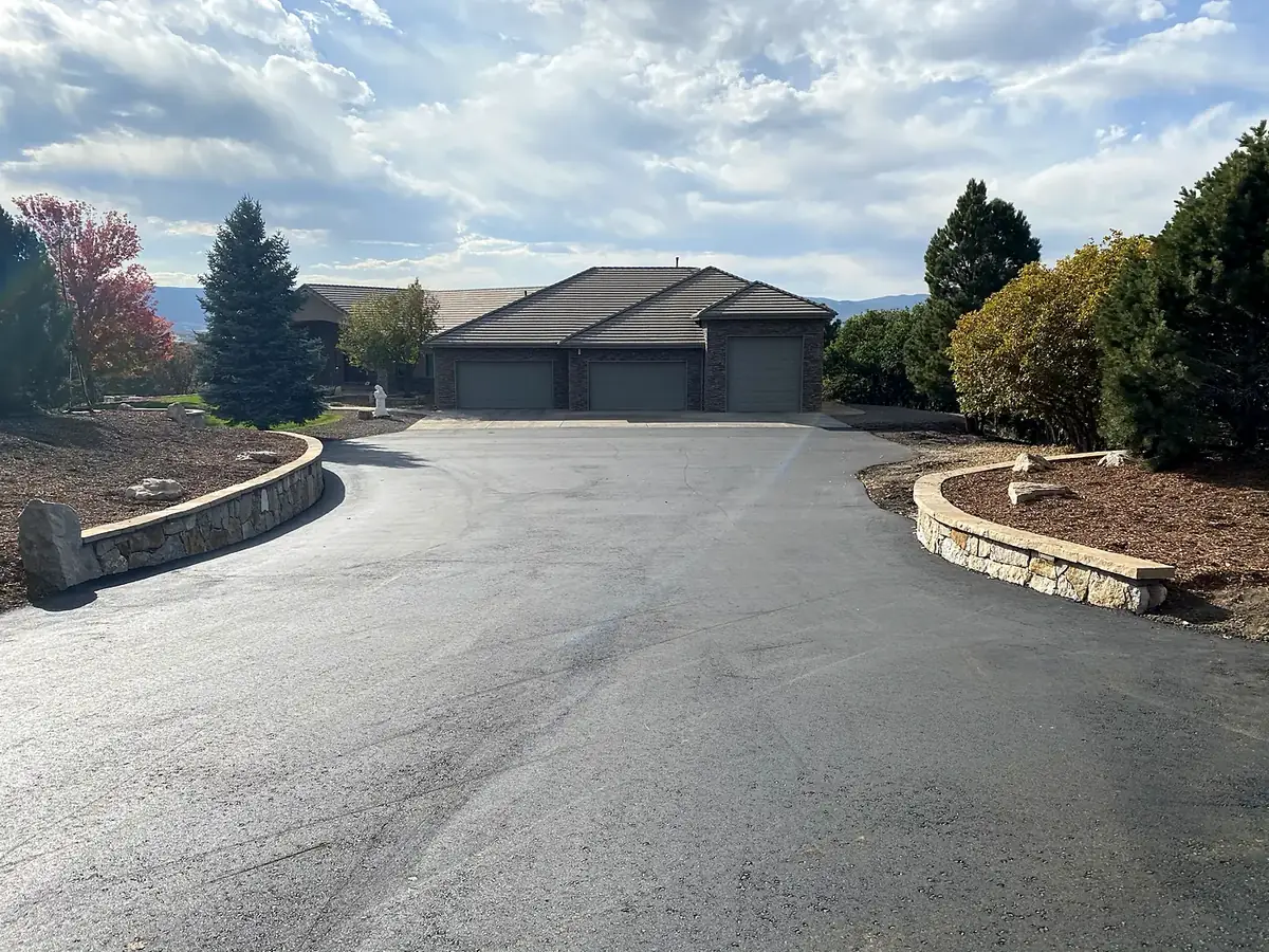 Finished asphalt driveway with a turnaround and low stone walls in front of a home, Salida, Colorado