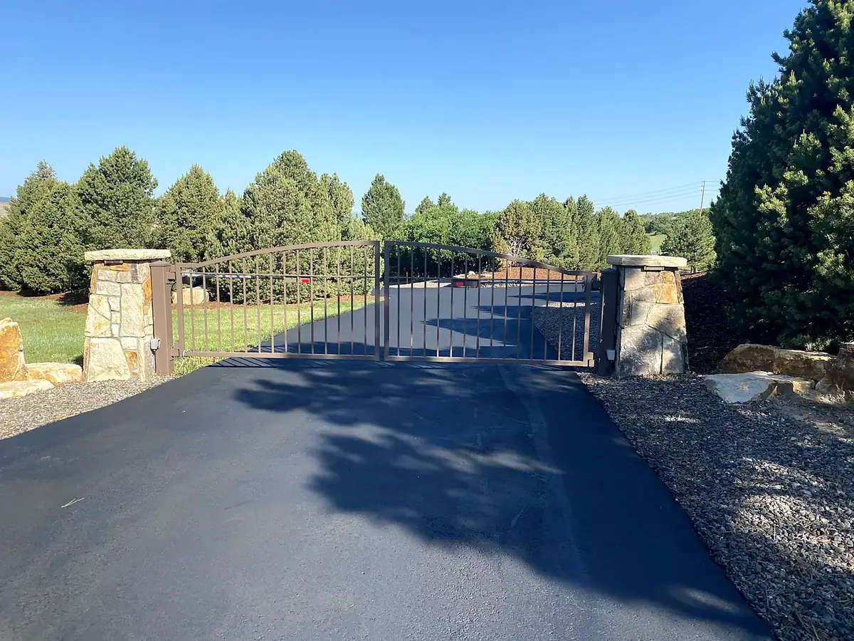 Asphalt driveway running through an iron gate between stone pillars, Salida, Colorado